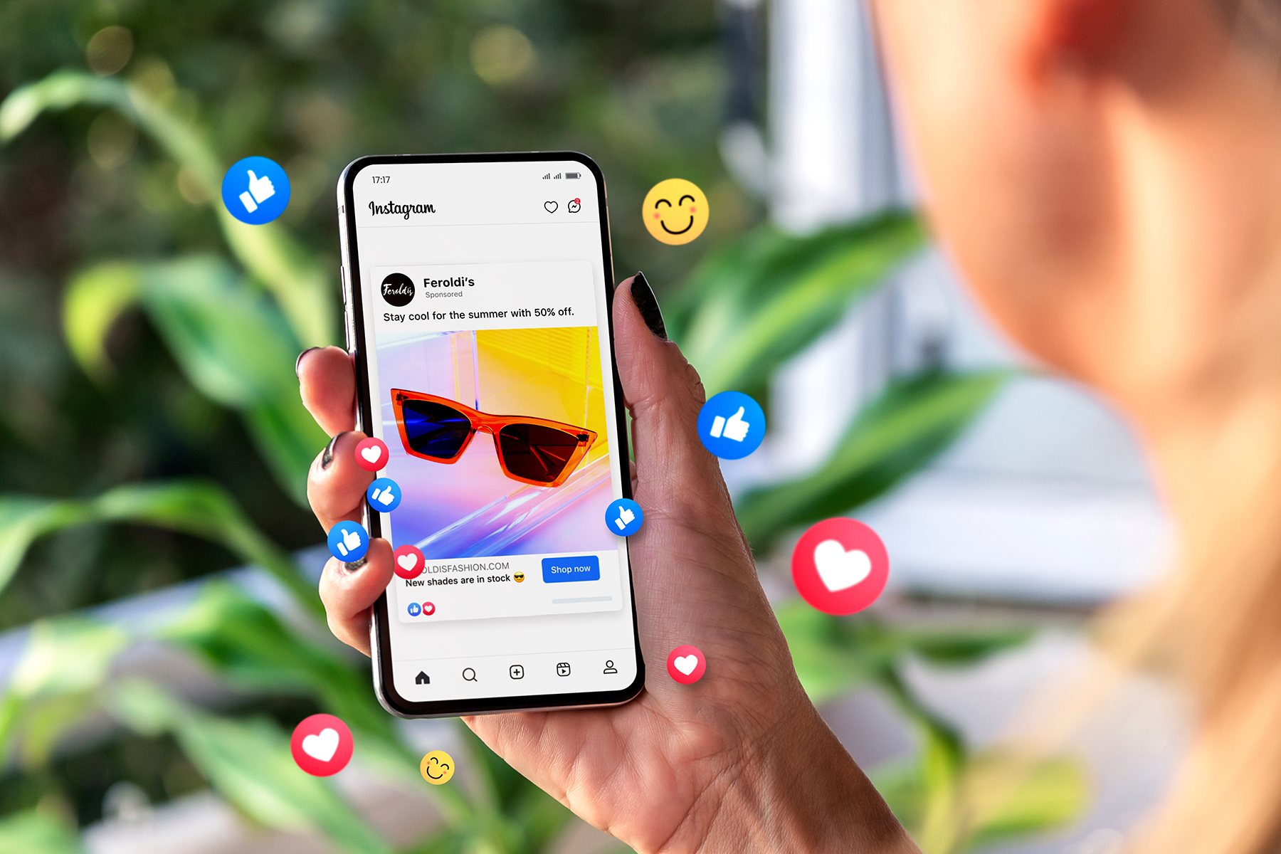 A hand is holding a smartphone displaying ads on an Instagram screen. The screen shows an example of advertising on the platform. The background is blurred.