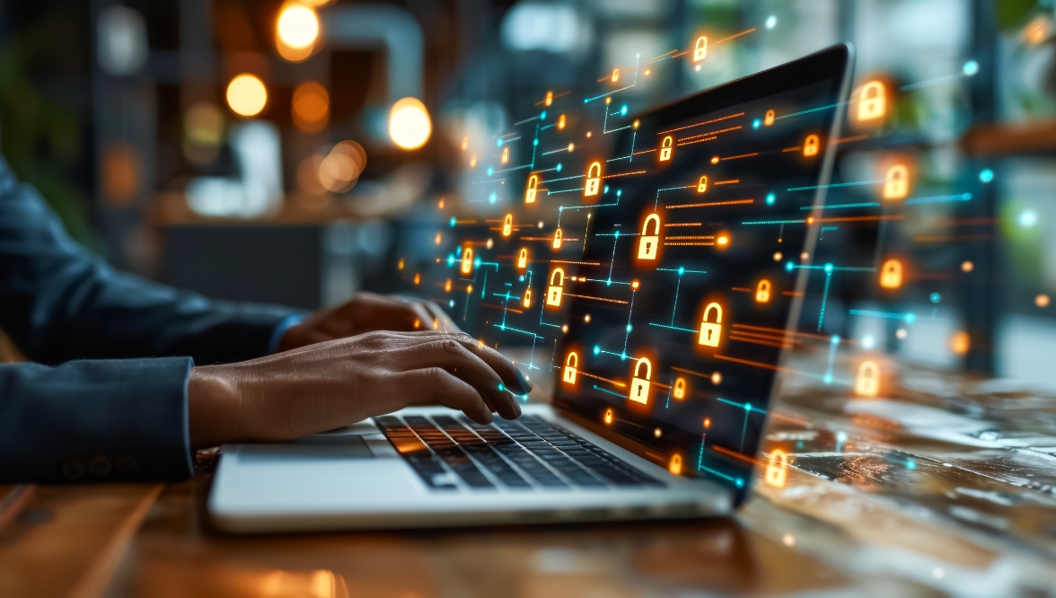 The hands of a person using a laptop with virtual padlock icons displayed on the screen, symbolizing cyber and data security.