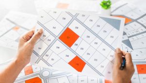 A close up of hands holding a colorful property zoning map over a desk with documents.