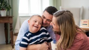 A mother and father smiling at their child who has Down syndrome.