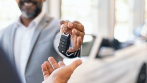 Car salesperson giving the keys to a new car to a customer.