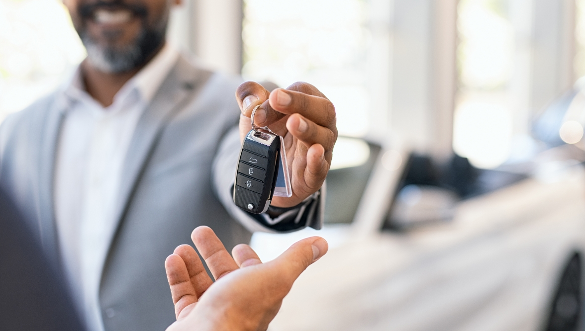 Car salesperson giving the keys to a new car to a customer.