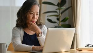 Woman thoughtfully looking at a laptop at home.