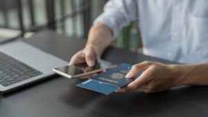 A man holds a passport in one hand and a smartphone in the other.