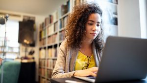 Young woman working on a laptop in a library.